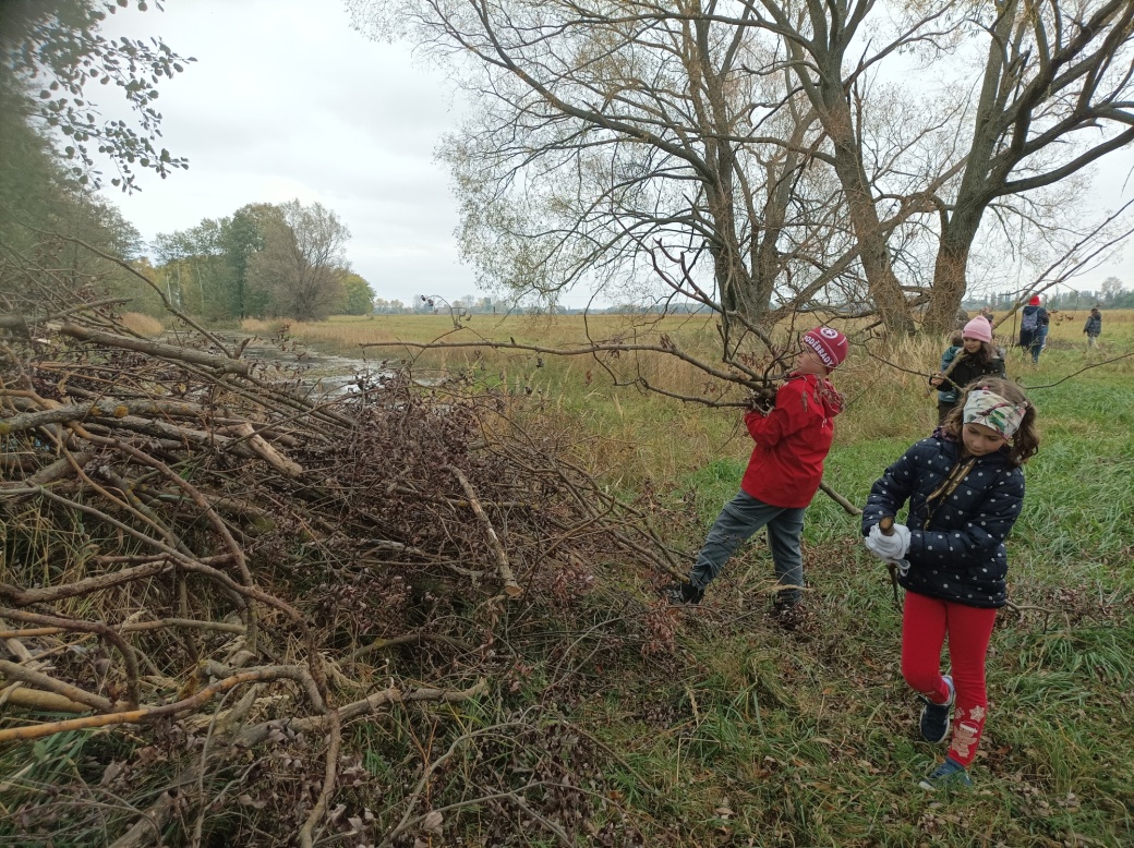Děti hází větve na hromadu.
