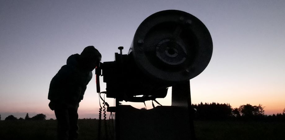Silueta dítěte, které nahlíží do hvězdářského dalekohledu.